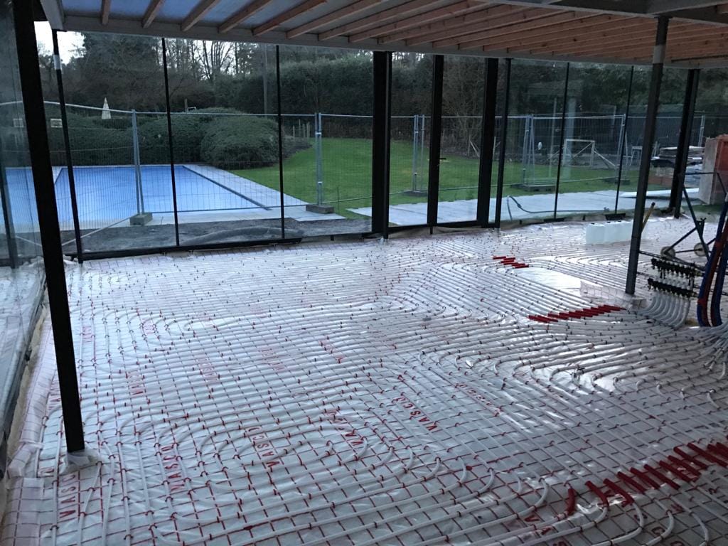 Vloerverwarmingsbuizen gelegd in een nieuwbouw met grote ramen